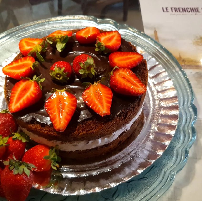 Bolo de chocolate coberto de morangos sobre prato de vidro