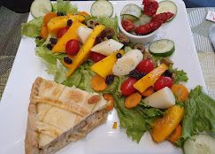 Salada com frutas e uma fatia de torta salgada
