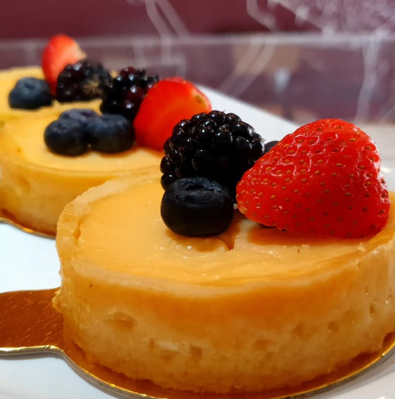 Tortinhas cremosas com amoras, mirtilos e morangos diante da parede ilustrada